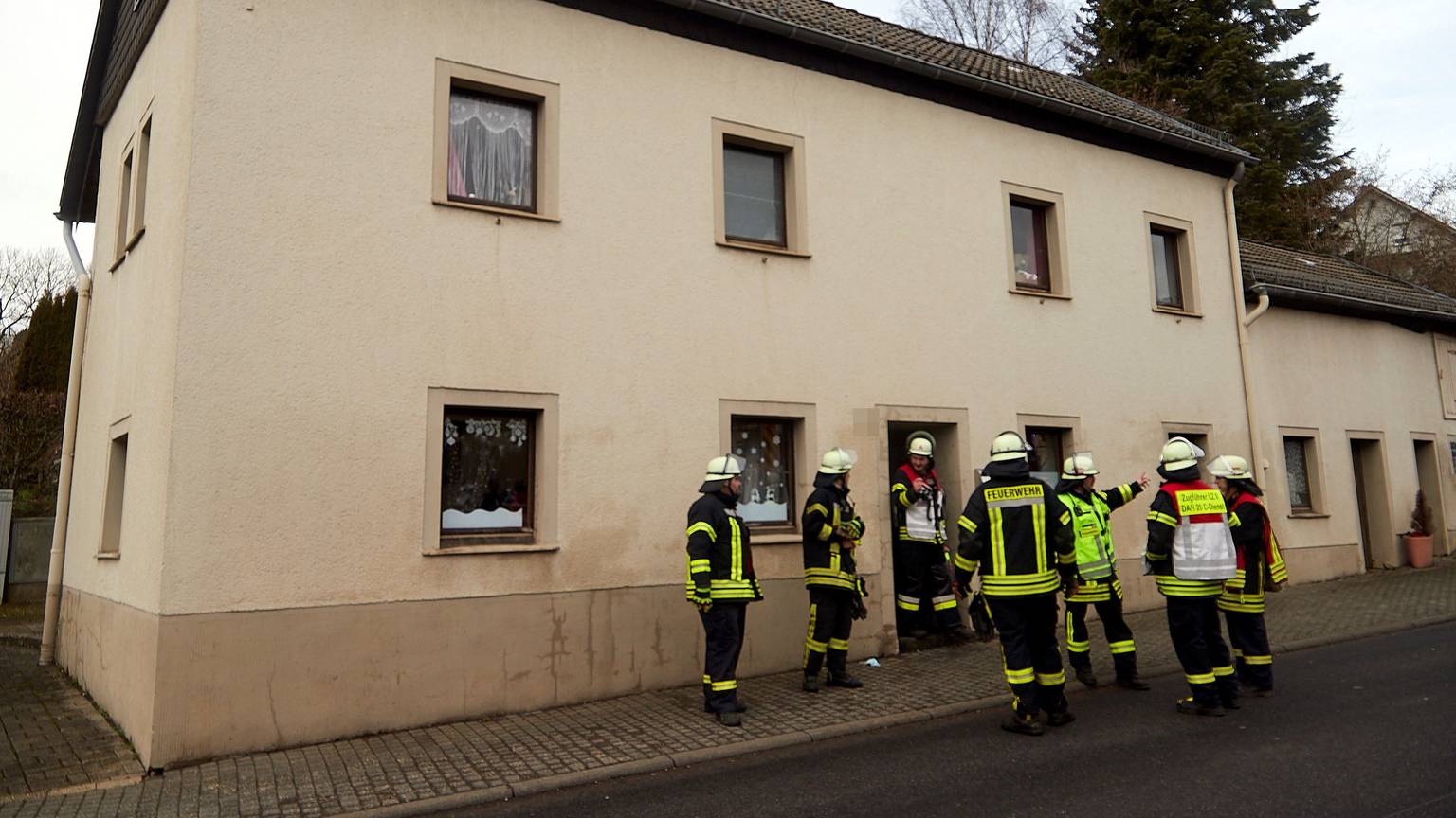 Feuerwehrleute stehen vor einem Haus in Dahlem.
