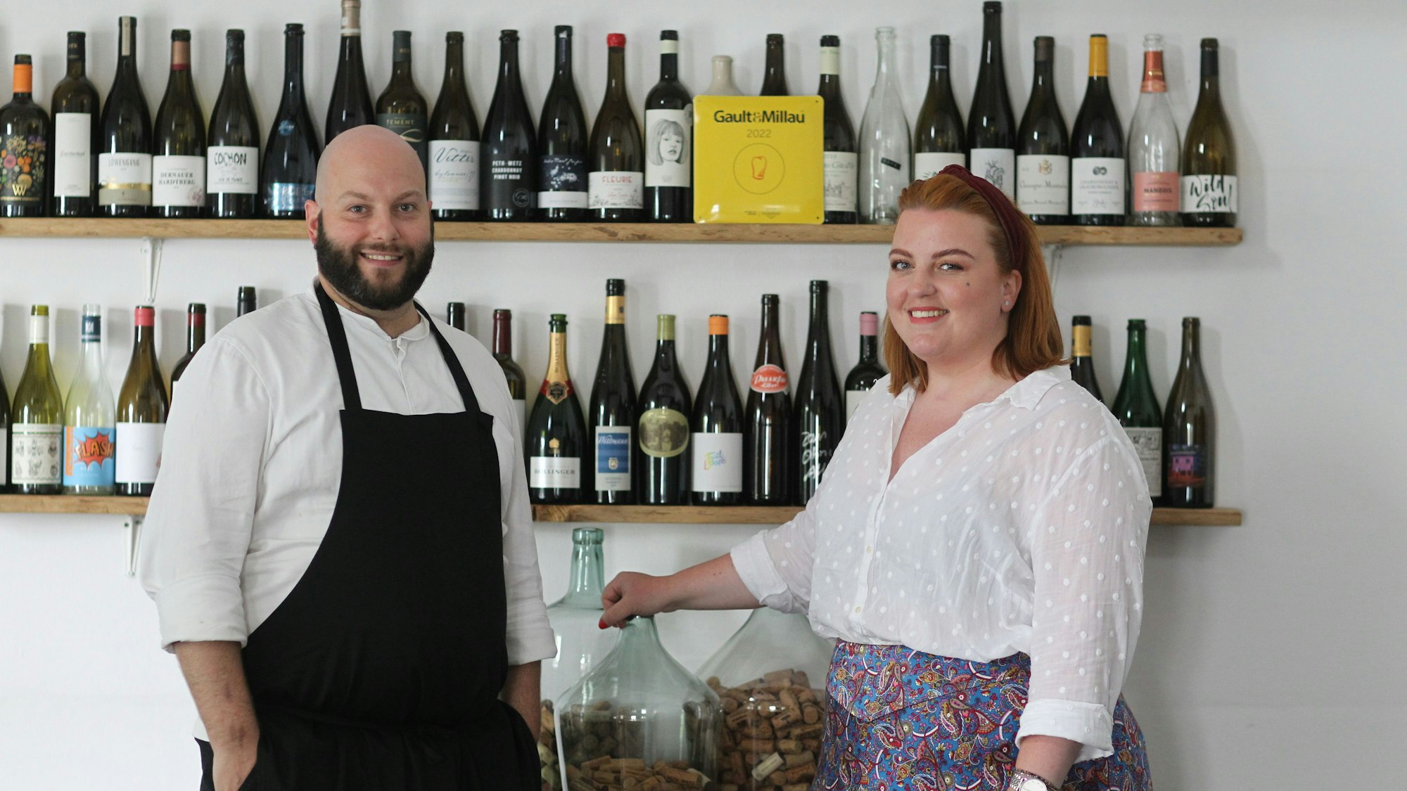 Daniel und Stephanie Lengsfeld stehen vor einem Weinregal in ihrem Gasthaus.