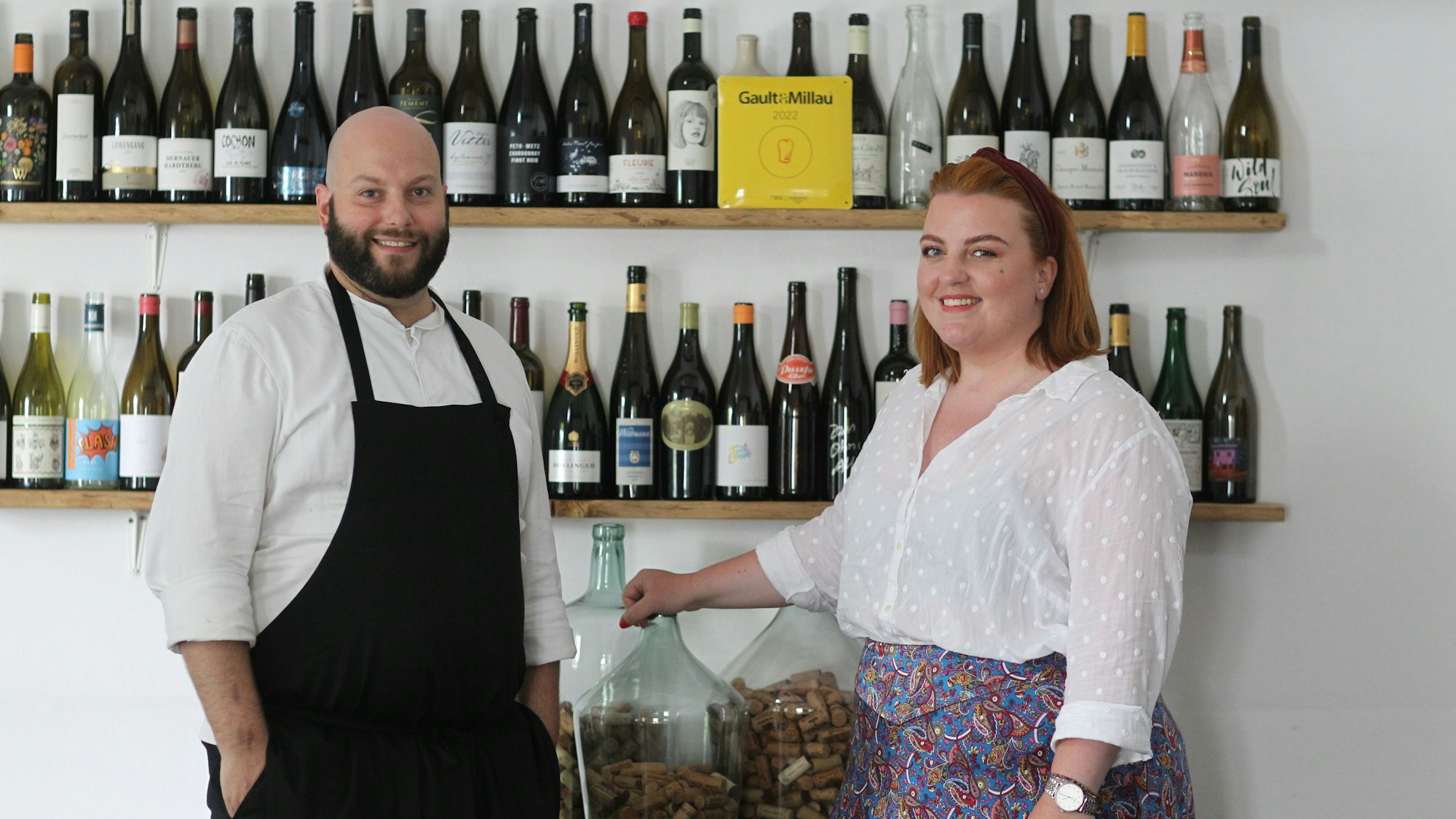 Daniel und Stephanie Lengsfeld aus dem Gasthaus Scheiderhöhe vor einer wand mit erlesenen Weinen.