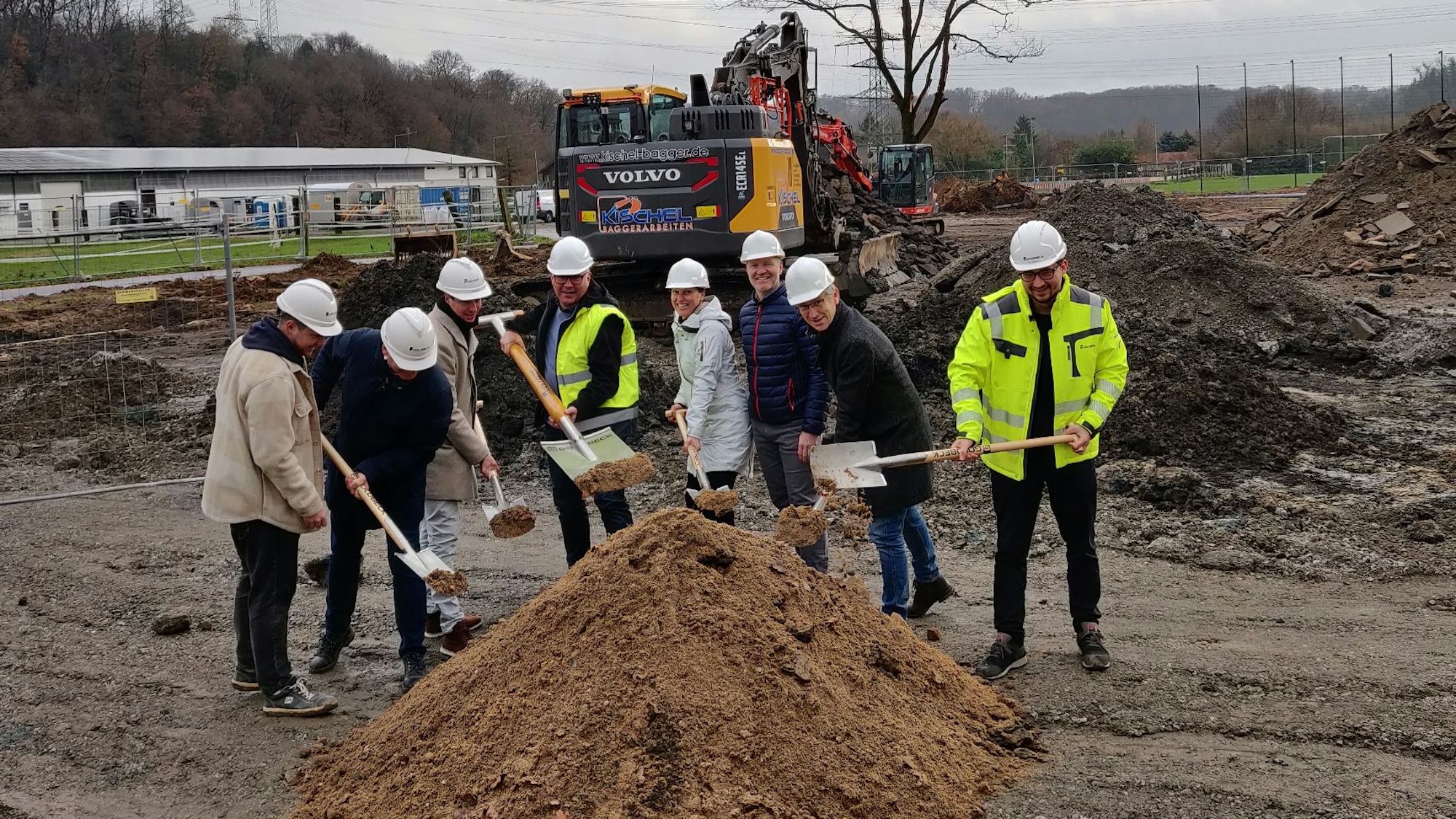 Mit Spaten in der Hand stehen vor einem Sandhaufen Roman Stach (Projektleiter Goldbeck), FB-Leiter Ingolf Bergerhoff, Stephan Bergmann (Amt für Gebäudewirtschaft), FB-Leiterin Mirjam Bosse, Bürgermeister Frank Steffes und Kämmerer Thomas Knabbe