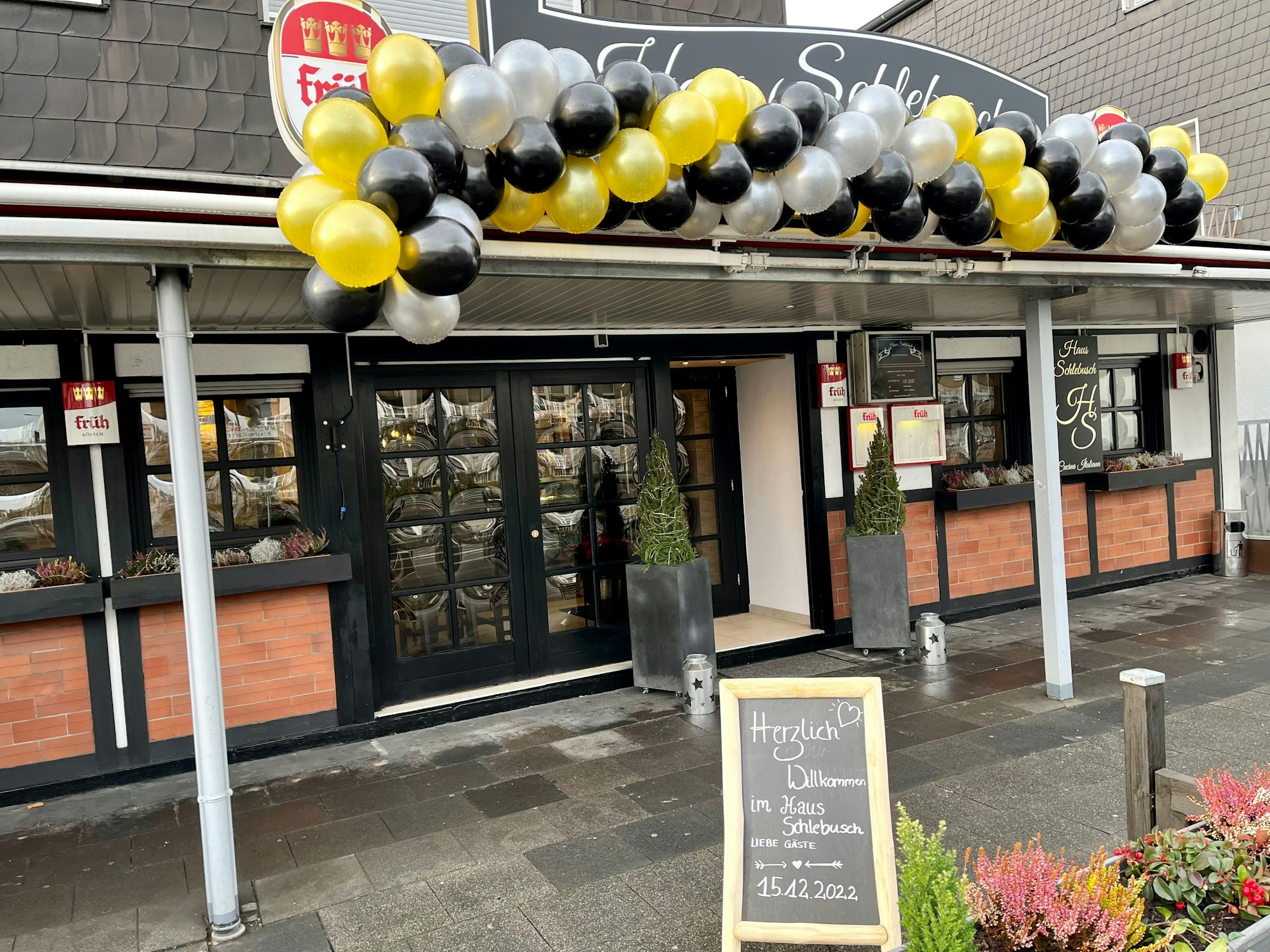 Schwarze, goldene und silberne Luftballons hängen über dem Schriftzug Haus Schlebsch