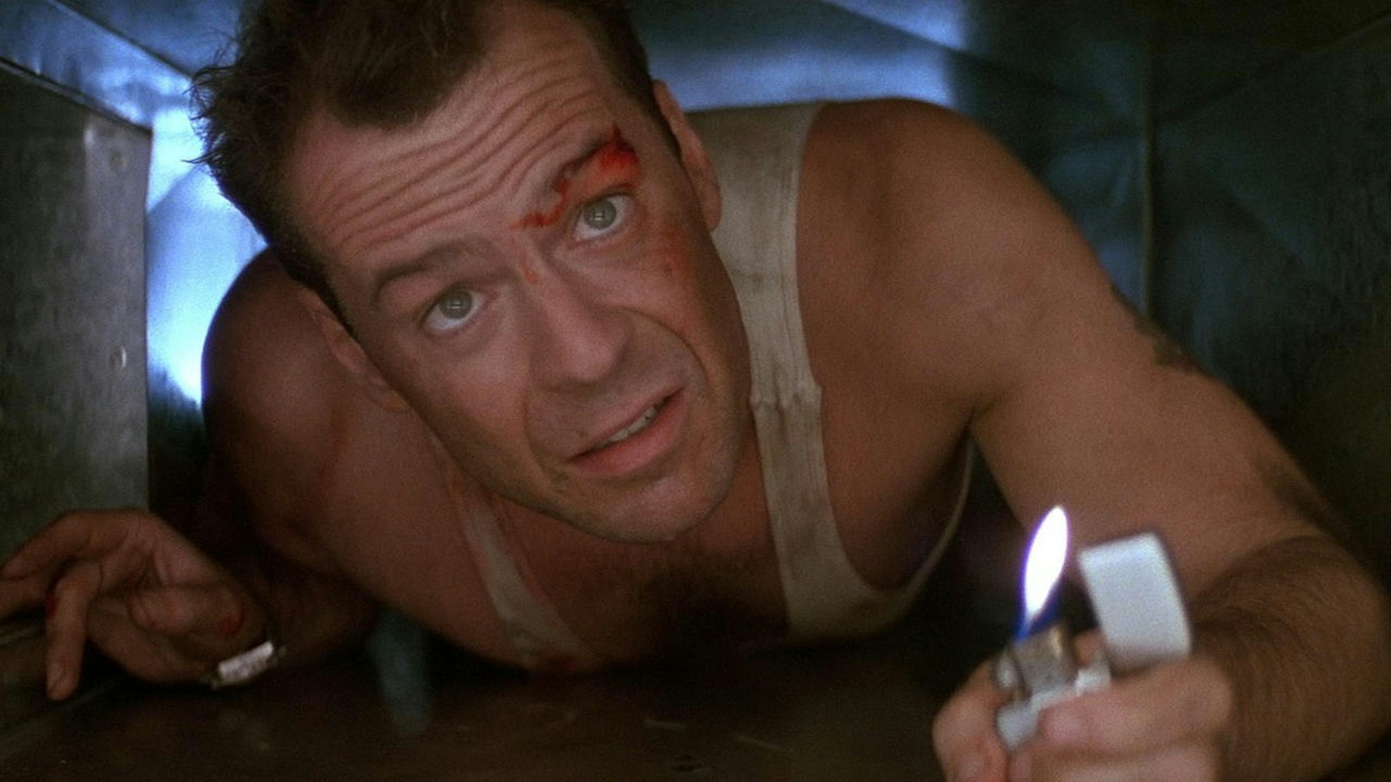Bruce Willis kriecht durch einen Luftschacht, vor sich hält ein Feuerzeug.