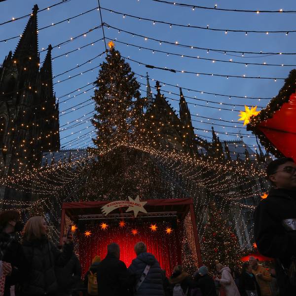 Die Spitzen des Kölner Dom erheben sich hinter dem Weihnachtsmarkt auf dem Roncalliplatz.