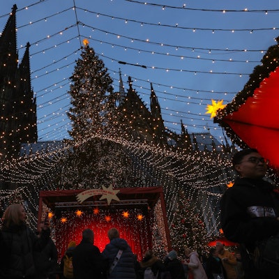 Die Spitzen des Kölner Dom erheben sich hinter dem Weihnachtsmarkt auf dem Roncalliplatz.