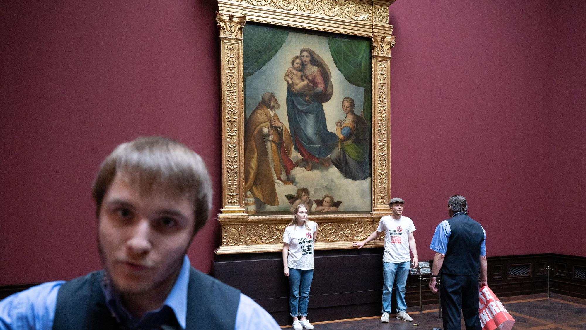 Zwei Umweltaktivisten der Gruppe Letzte Generation stehen in der Gemäldegalerie Alte Meister an dem Gemälde Sixtinische Madonna von Raffael.