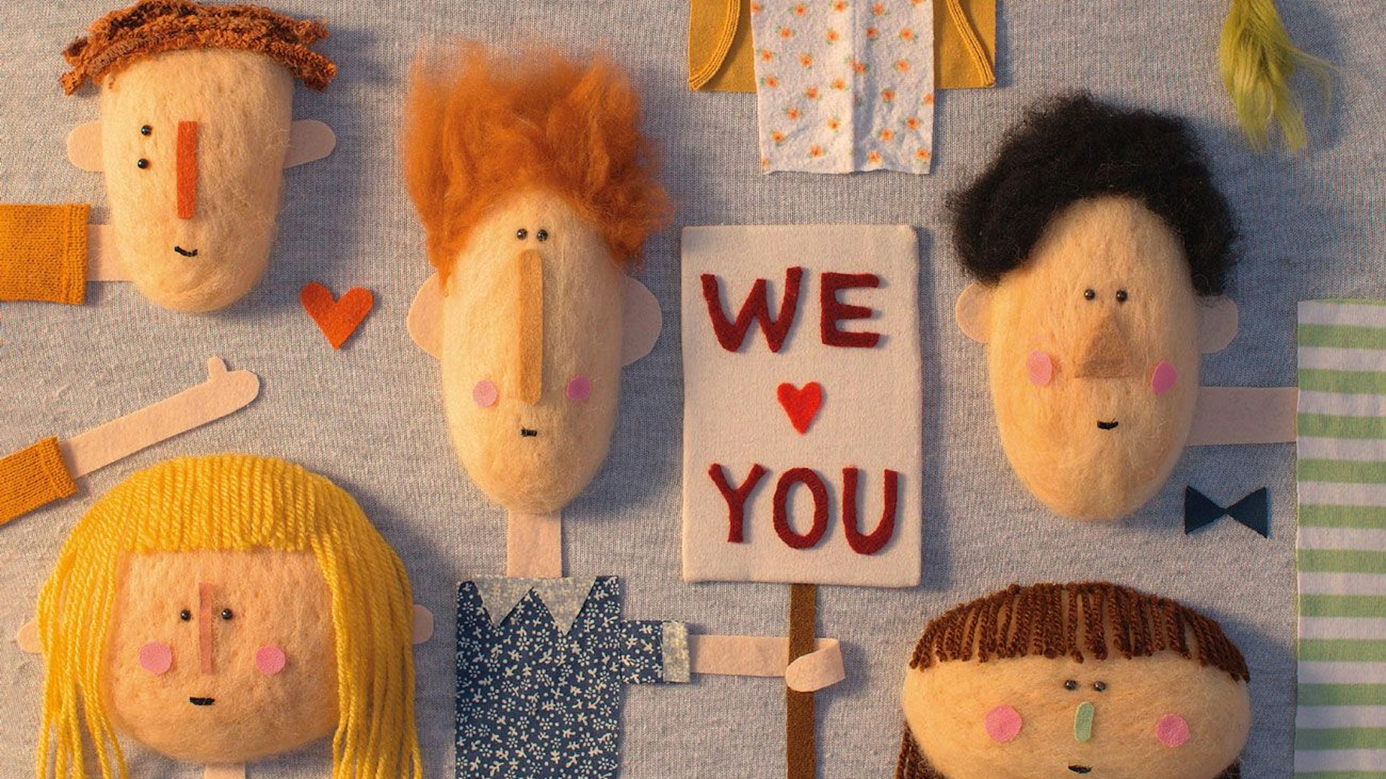 Viele Gesichter und ein Schild mit der Aufschrift We love You, Collage aus Stoff