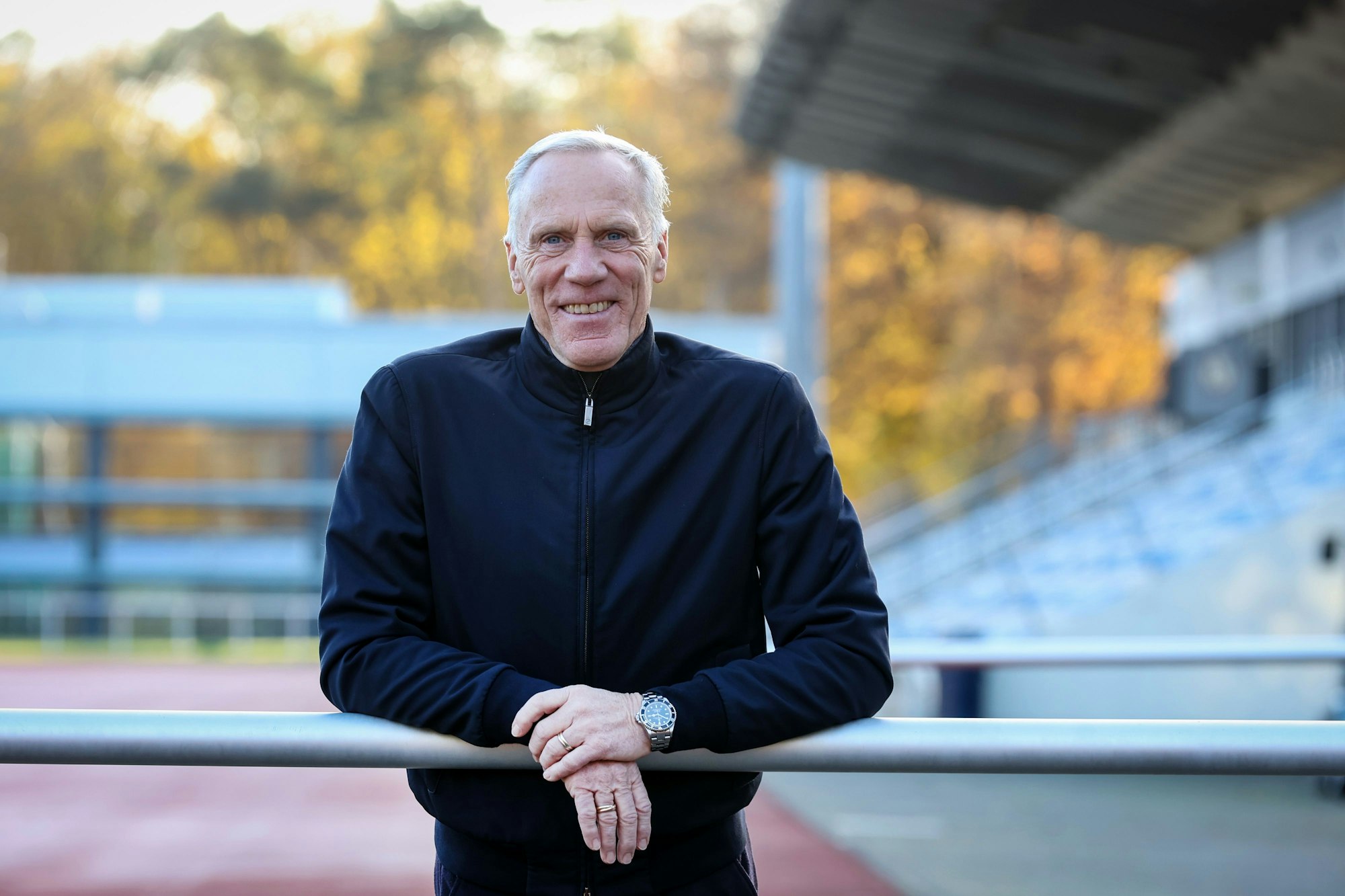 Ingo Froböse steht auf einem Sportplatz und guckt in die Kamera.