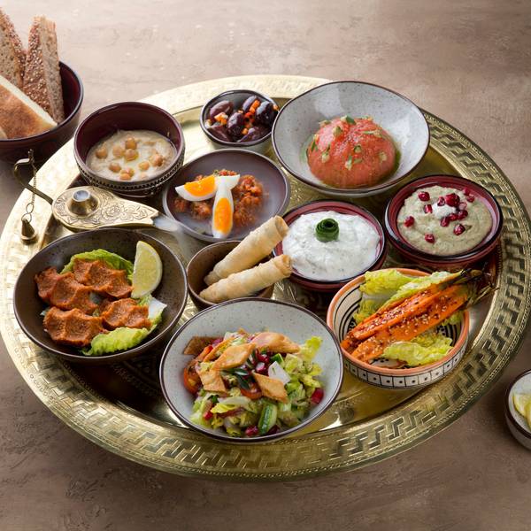 Mezze-Platte, angerichtete Speisen in kleinen Schälchen auf einem Tablett mit Brot.