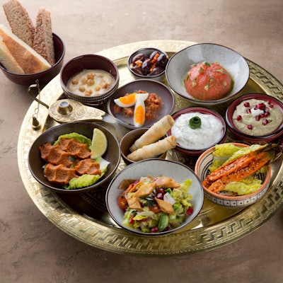 Mezze-Platte, angerichtete Speisen in kleinen Schälchen auf einem Tablett mit Brot.