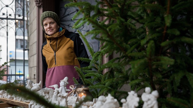 Monika Lioba Lang steht neben einem Tannenbaum hinter Krippenfiguren aus Ton.