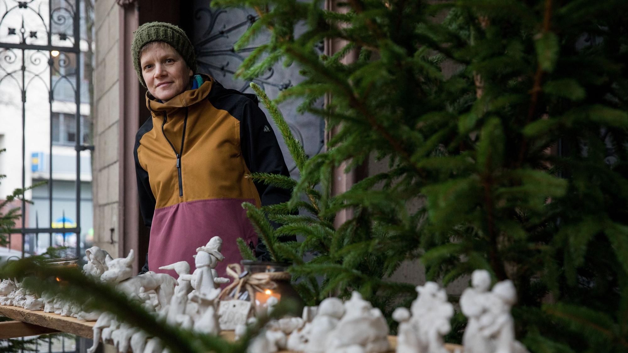 Monika Lioba Lang steht neben einem Tannenbaum hinter Krippenfiguren aus Ton.