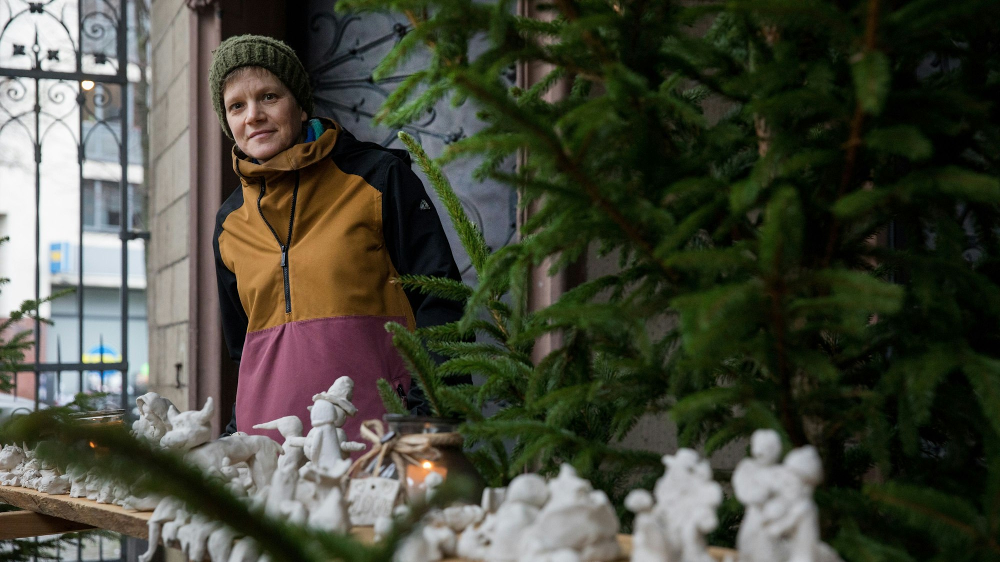 Monika Lioba Lang steht neben einem Tannenbaum hinter Krippenfiguren aus Ton.