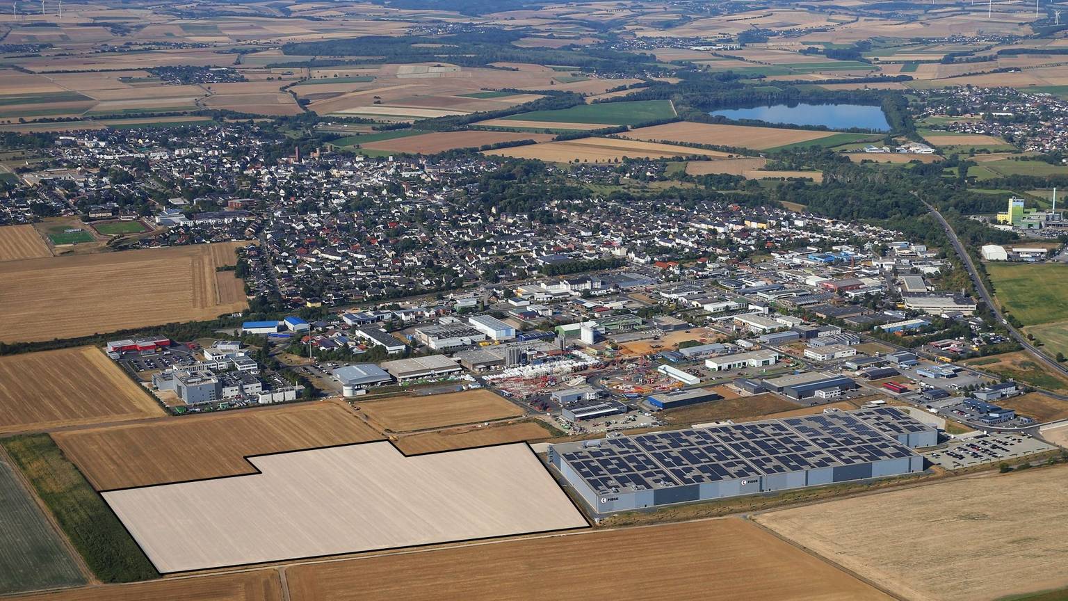 Drohnenansicht des Gewerbegebiets der Stadt Zülpich mit vielen Fabrikhallen und Feldern.