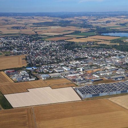 Drohnenansicht des Gewerbegebiets der Stadt Zülpich mit vielen Fabrikhallen und Feldern.