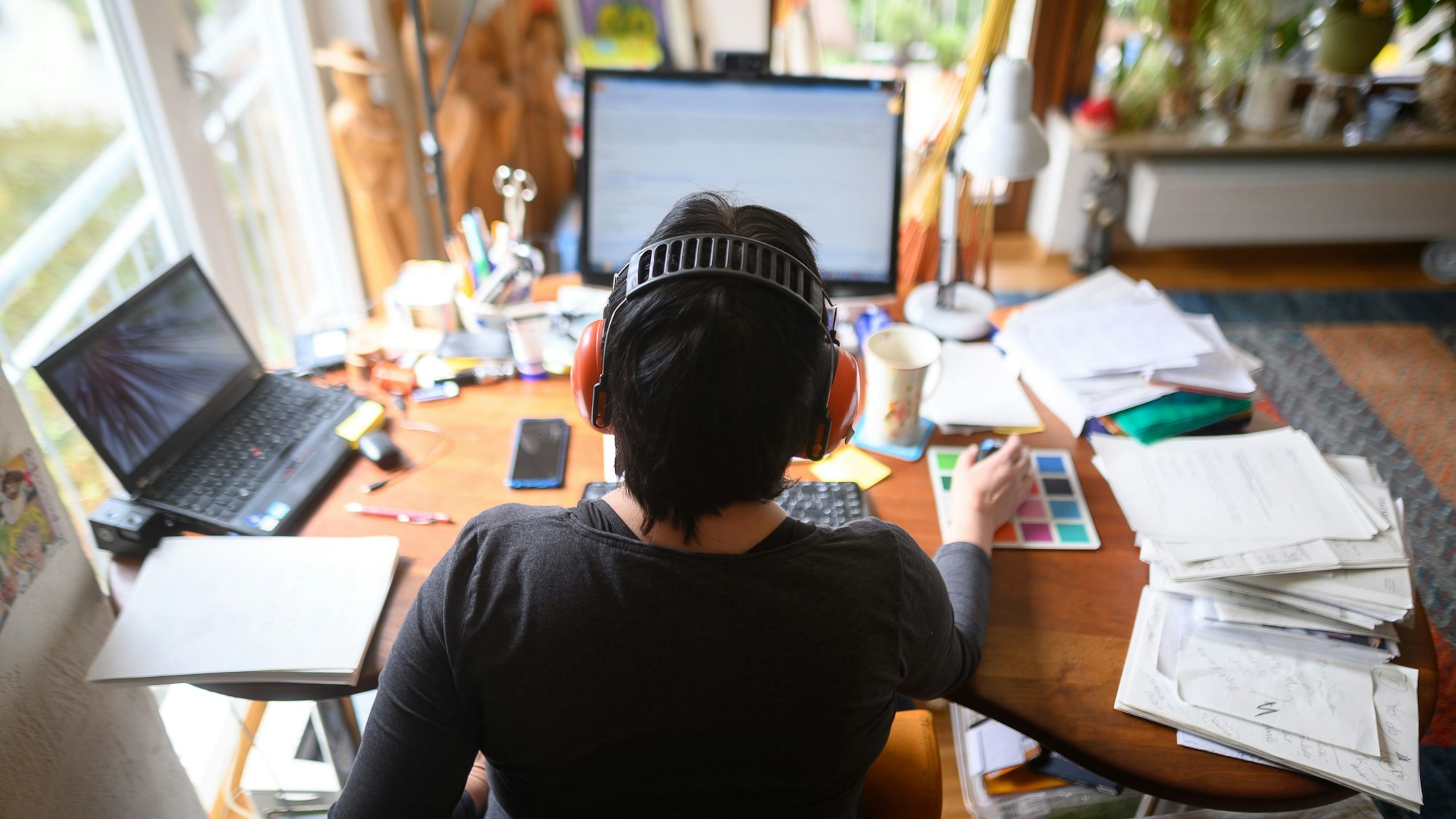Eine Frau arbeitet mit Hörschutz im Homeoffice.