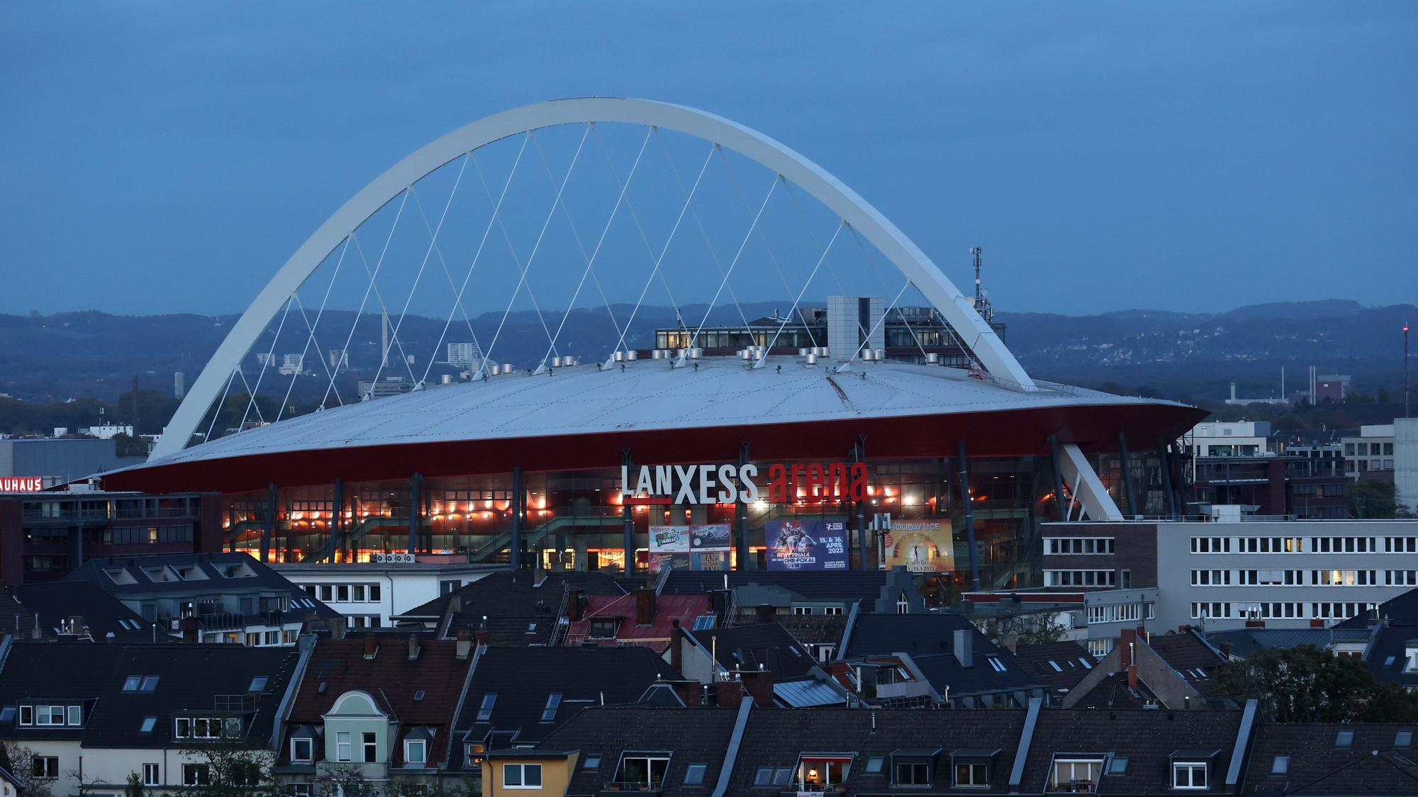 Die Lanxess-Arena von einem erhöhten Standpunkt gesehen, im Vordergrund Häuser.