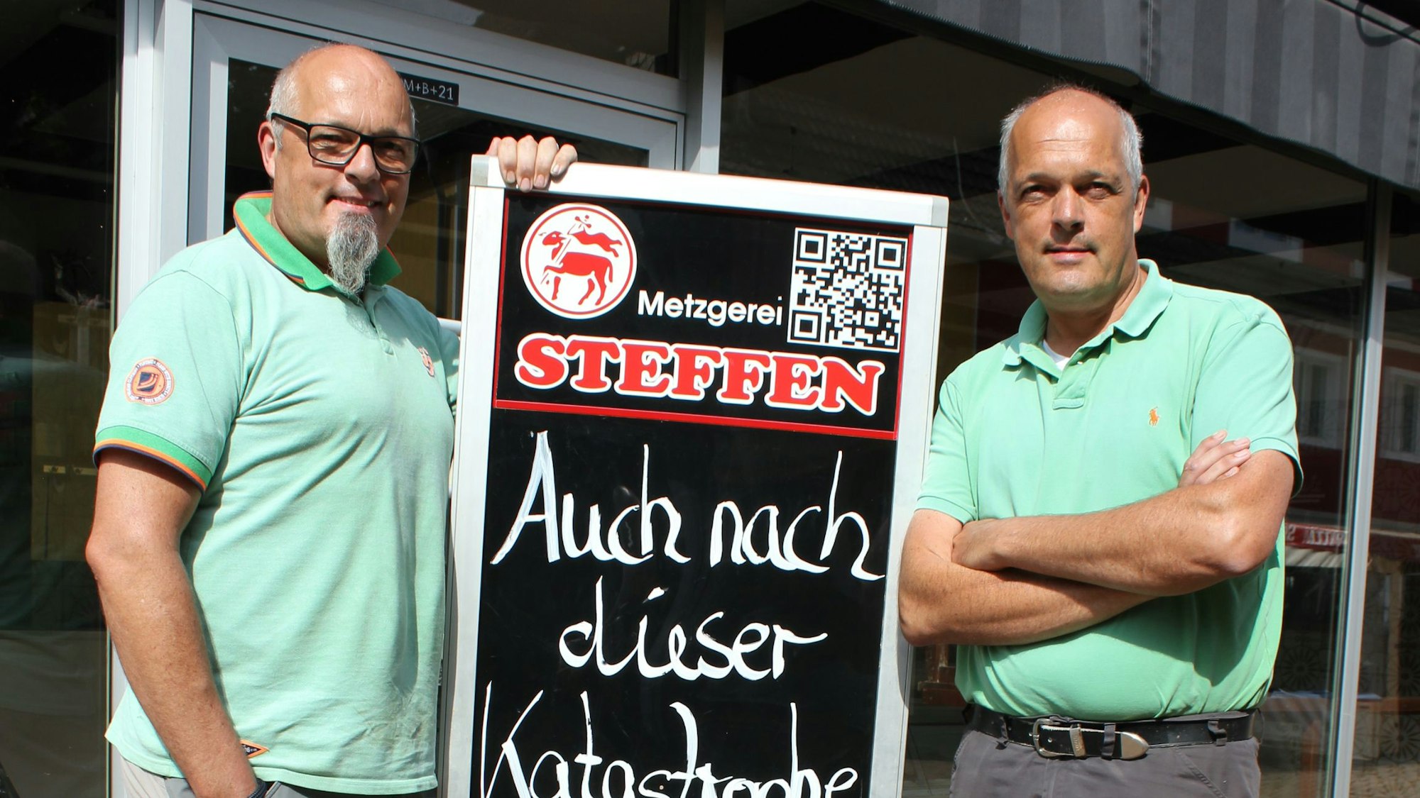 Metzger in Schleiden stehen vor einem Metzgereischild.