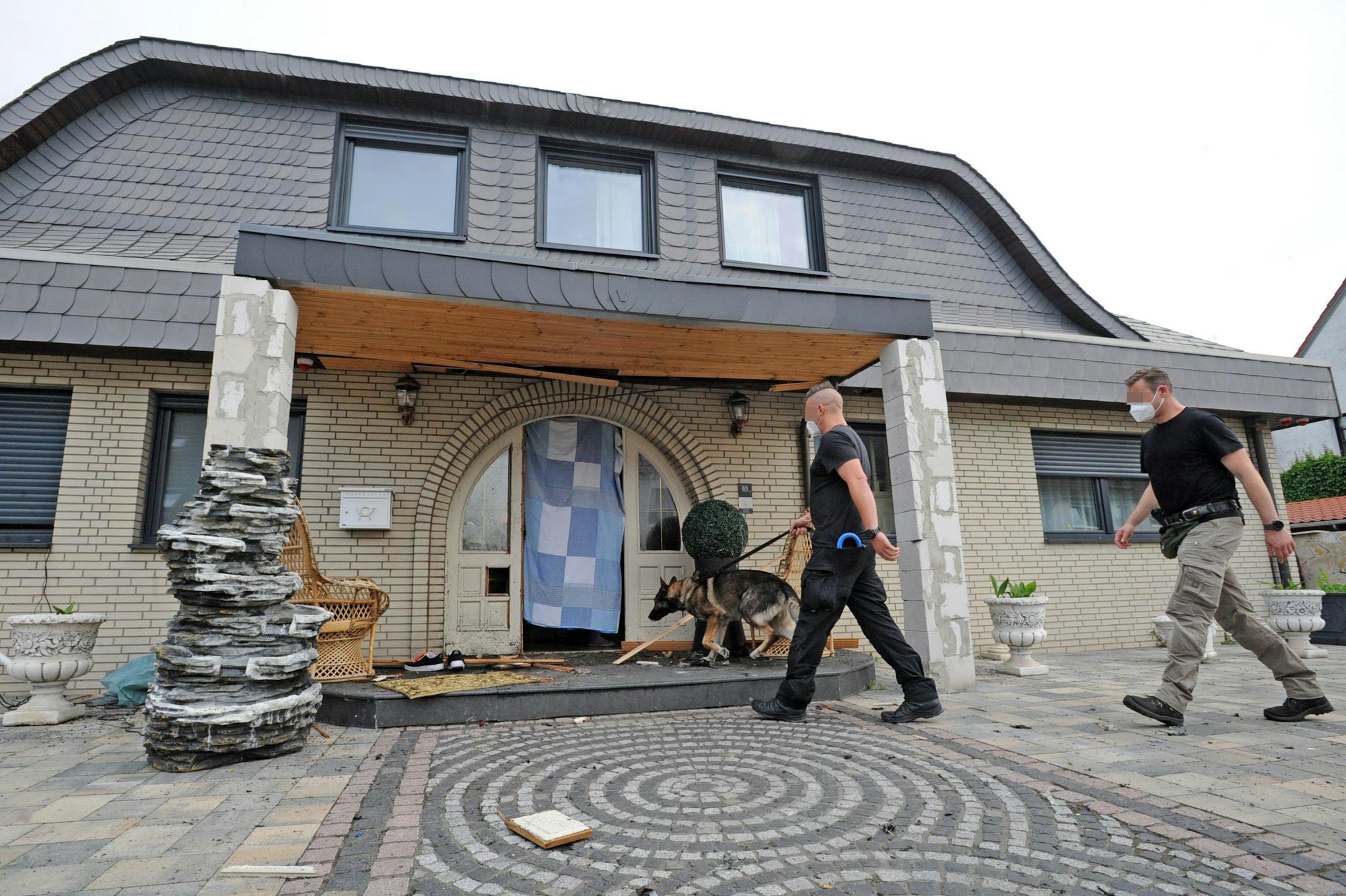 Polizisten gehen mit einem Hund bei einer Razzia durch die Eingangstür der Al-Zein-Villa.