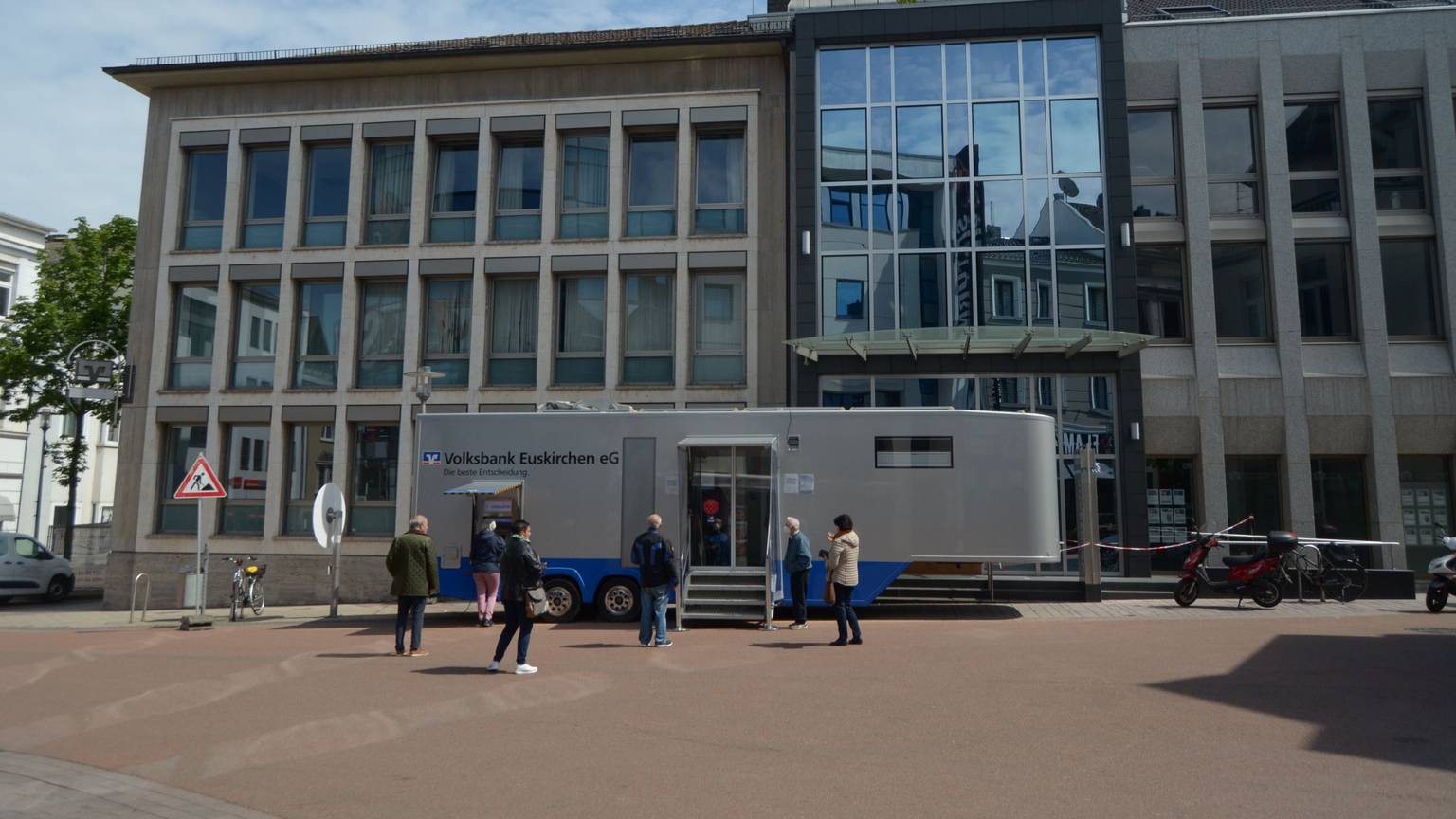 Ein Anhänger der Volksbank Euskirchen steht vor einem abgesperrten Gebäude.