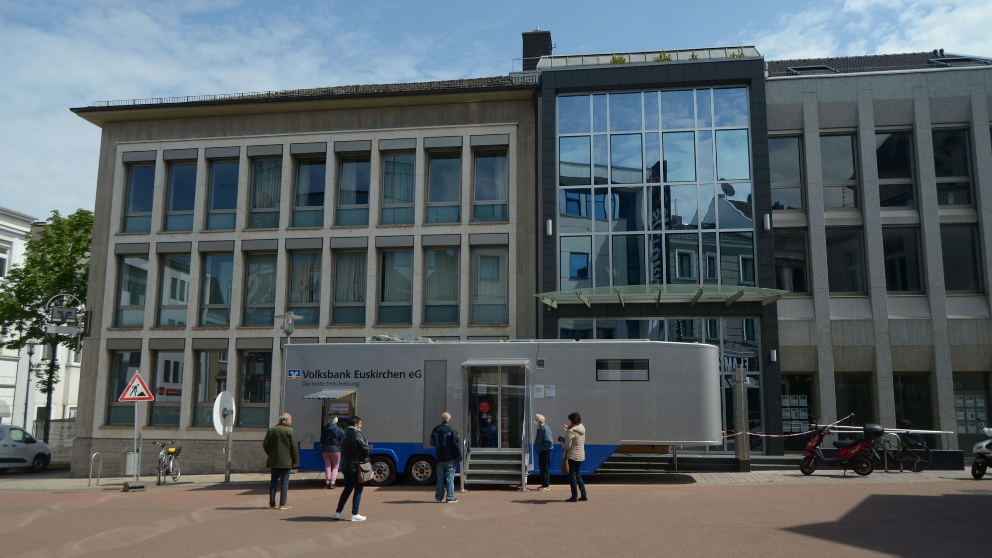 Ein Anhänger der Volksbank Euskirchen steht vor einem abgesperrten Gebäude.
