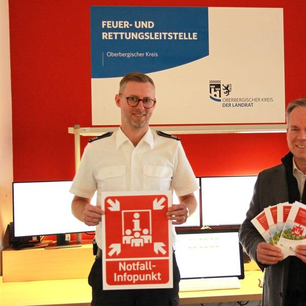 Leitstellen-Chef Julian Seeger (l.) und Kreisdirektor Klaus Grootens halten ein knallrote Symbol in der Hand, das bei einem Stromausfall auf Notfallpunkte hinweisen soll.