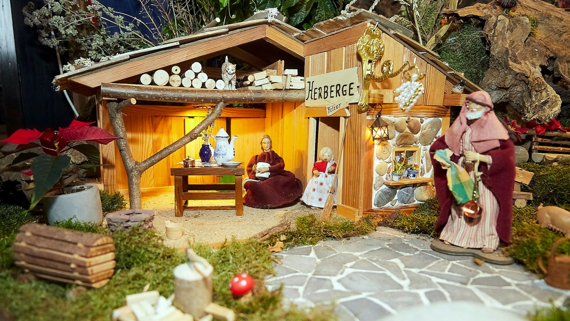 Ein Holzhaus mit Figuren ist in der Krippe zu sehen.