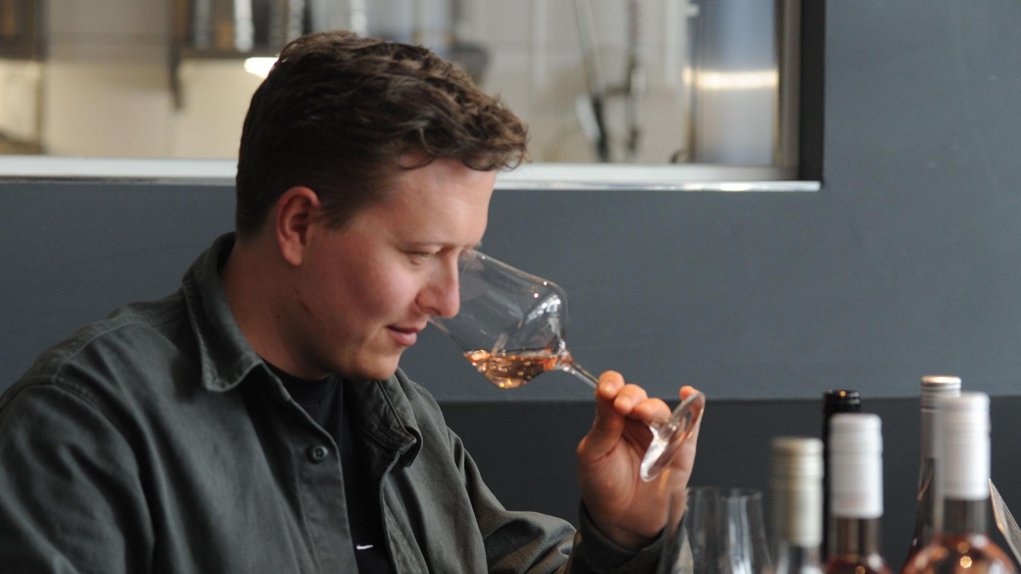Mann riecht den Roséwein in einem Weinglas.