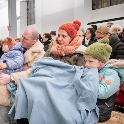 Kirchbesucher haben sich mit Decken eingehüllt.