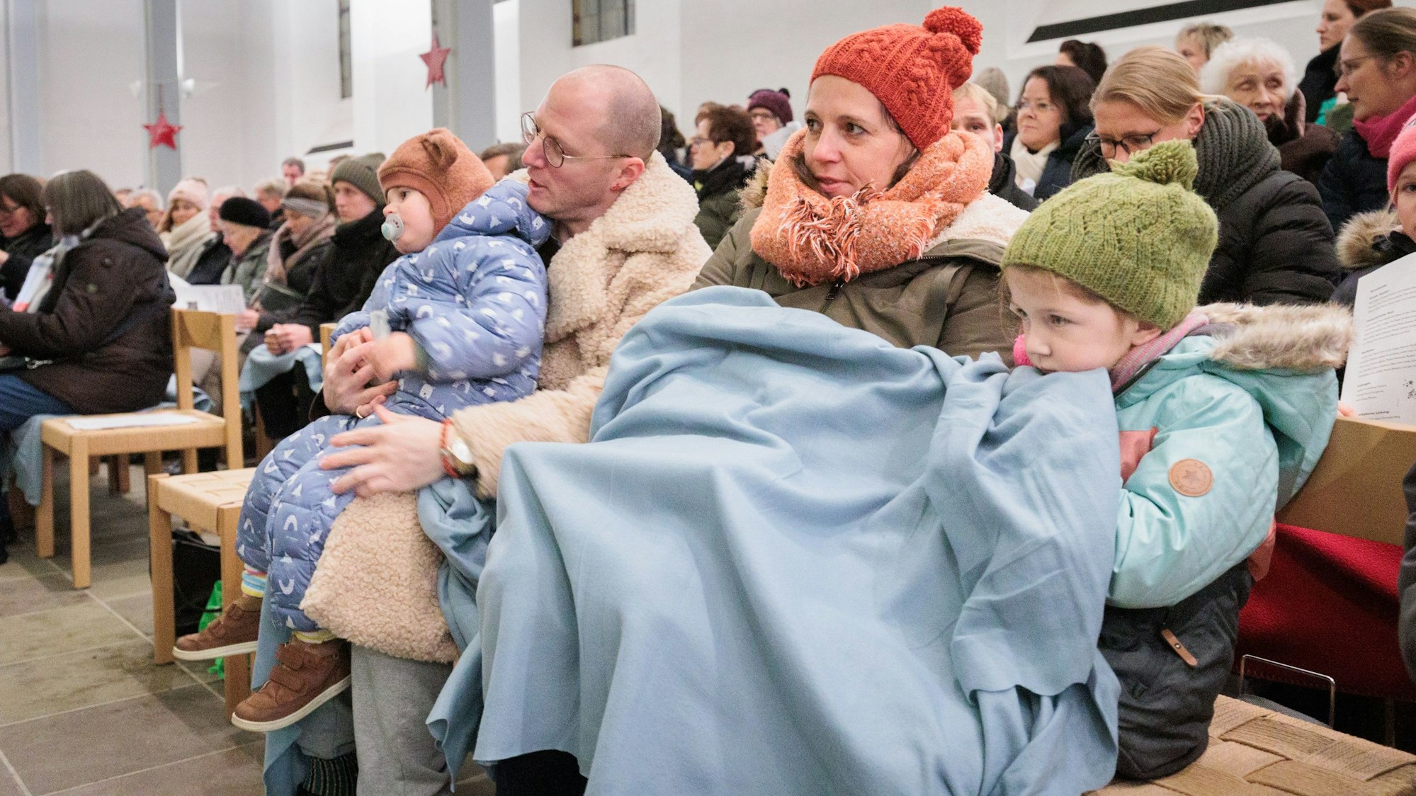 Kirchbesucher haben sich mit Decken eingehüllt.