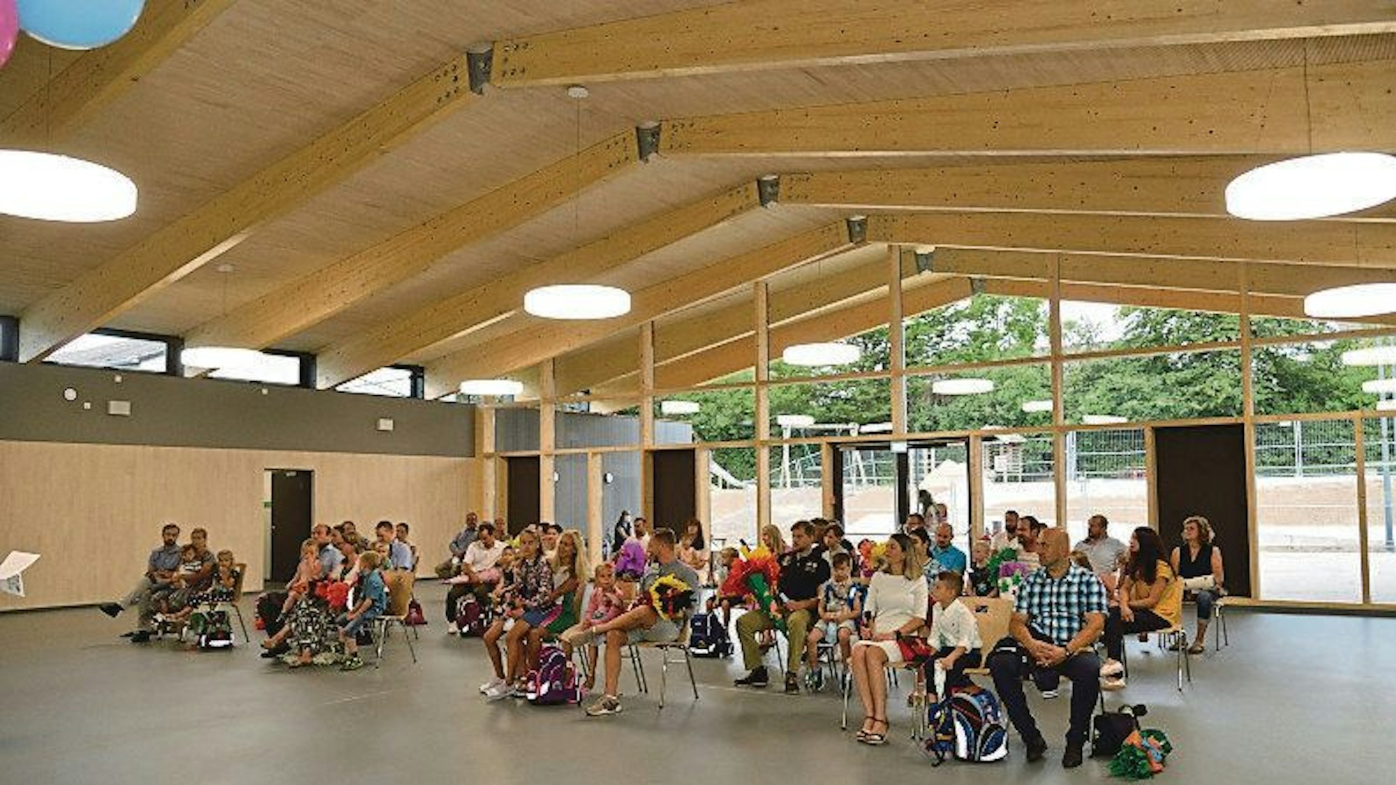 In einem großen Raum in der neu gebauten Grundschule in Neschen sitzen viele Menschen.