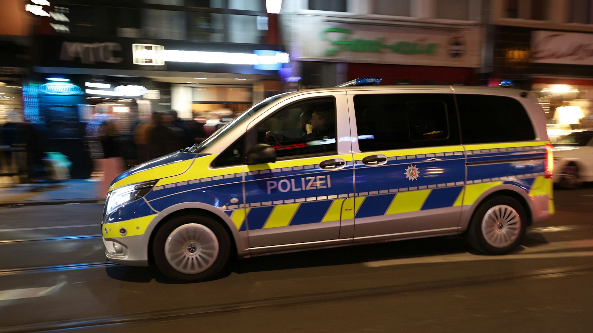 Ein Streifenwagen fährt schnell über eine Straße bei Nacht