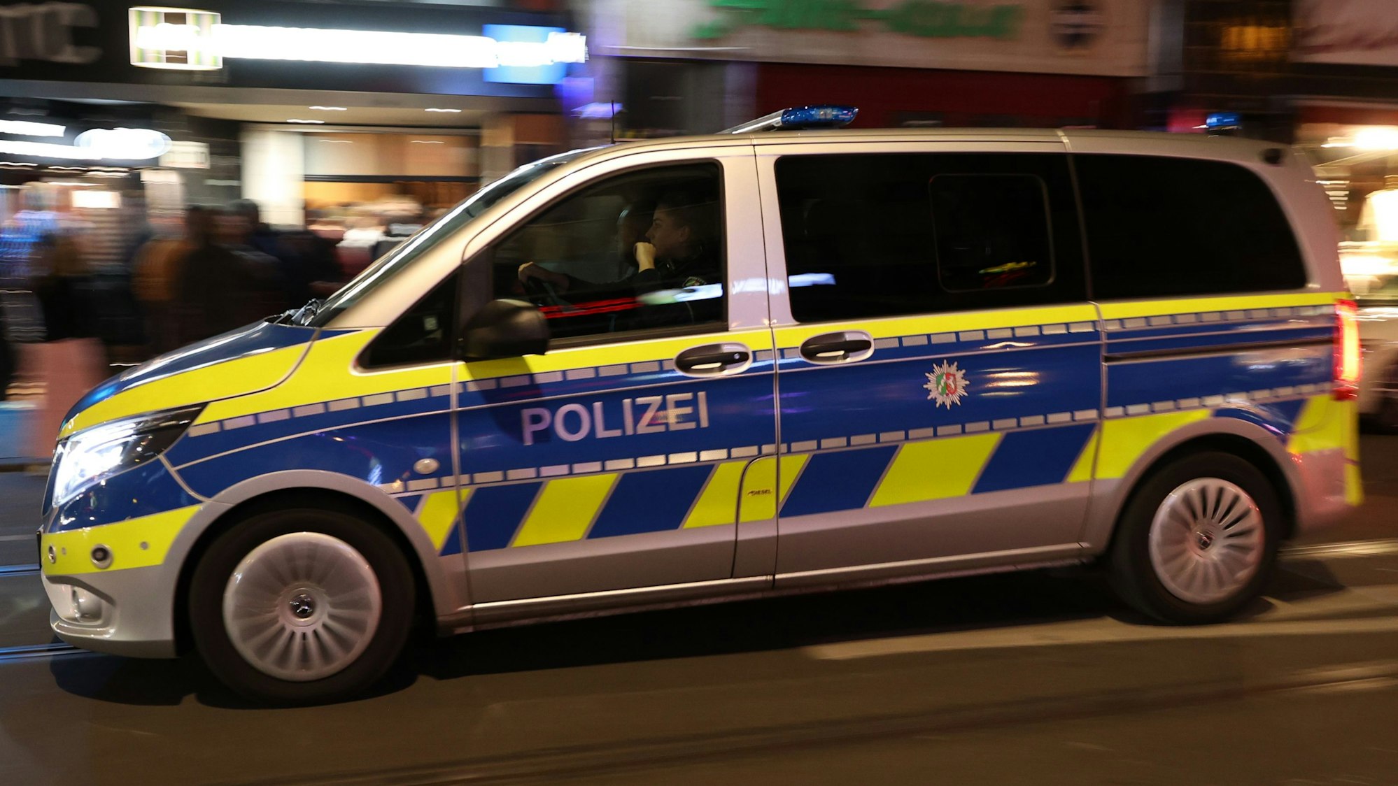 Ein Polizeifahrzeug bei Nacht. Im Hintergrund Leuchtreklame.