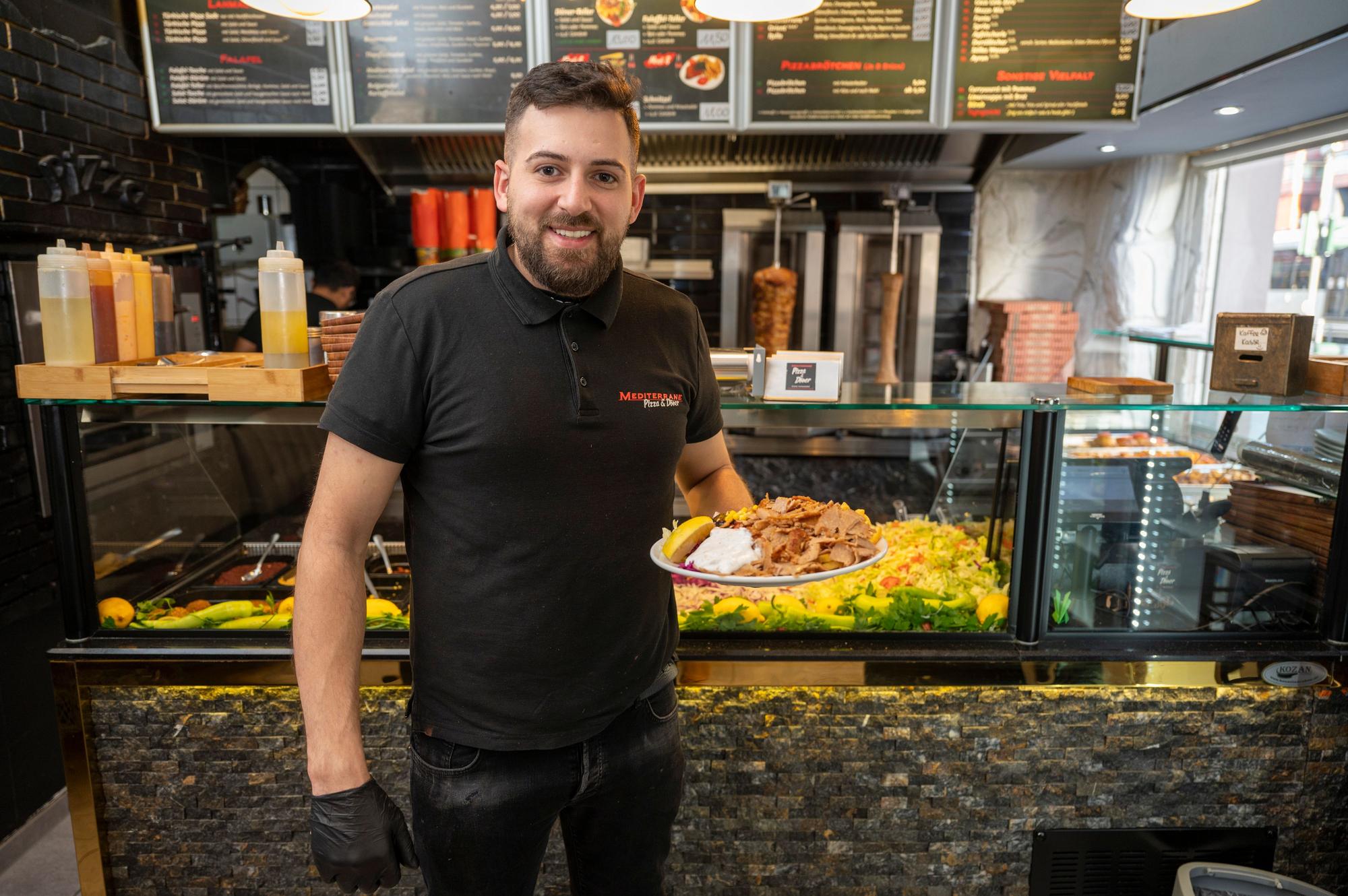 Fatih Yildirim steht mit einem Döner-Teller in der Hand in seinem Imbiss.