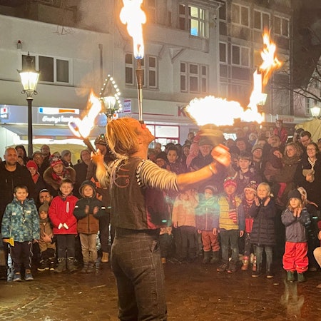 Ein Feuerkünstler wird von Kindern und Erwachsenen bestaunt.