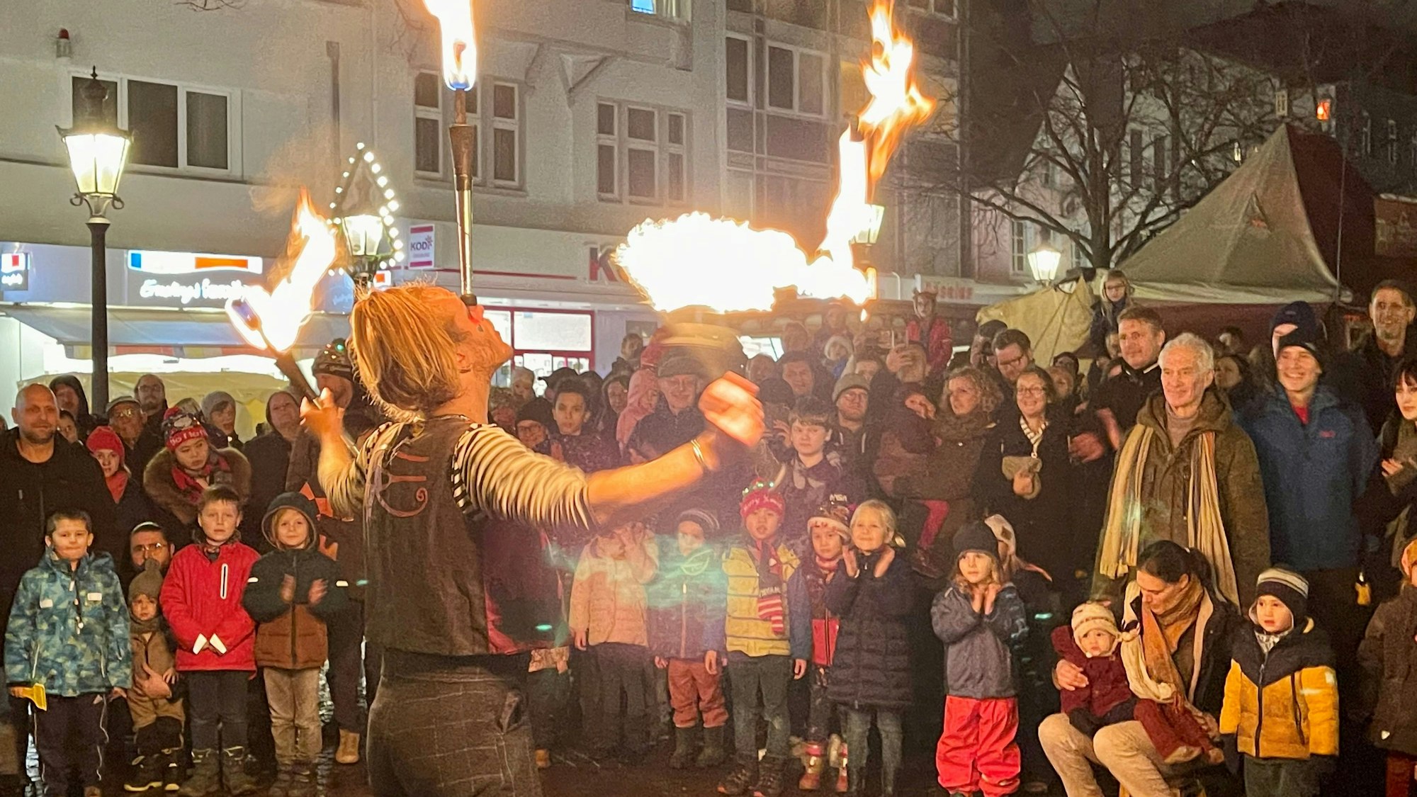 Ein Feuerkünstler wird von Kindern und Erwachsenen bestaunt.