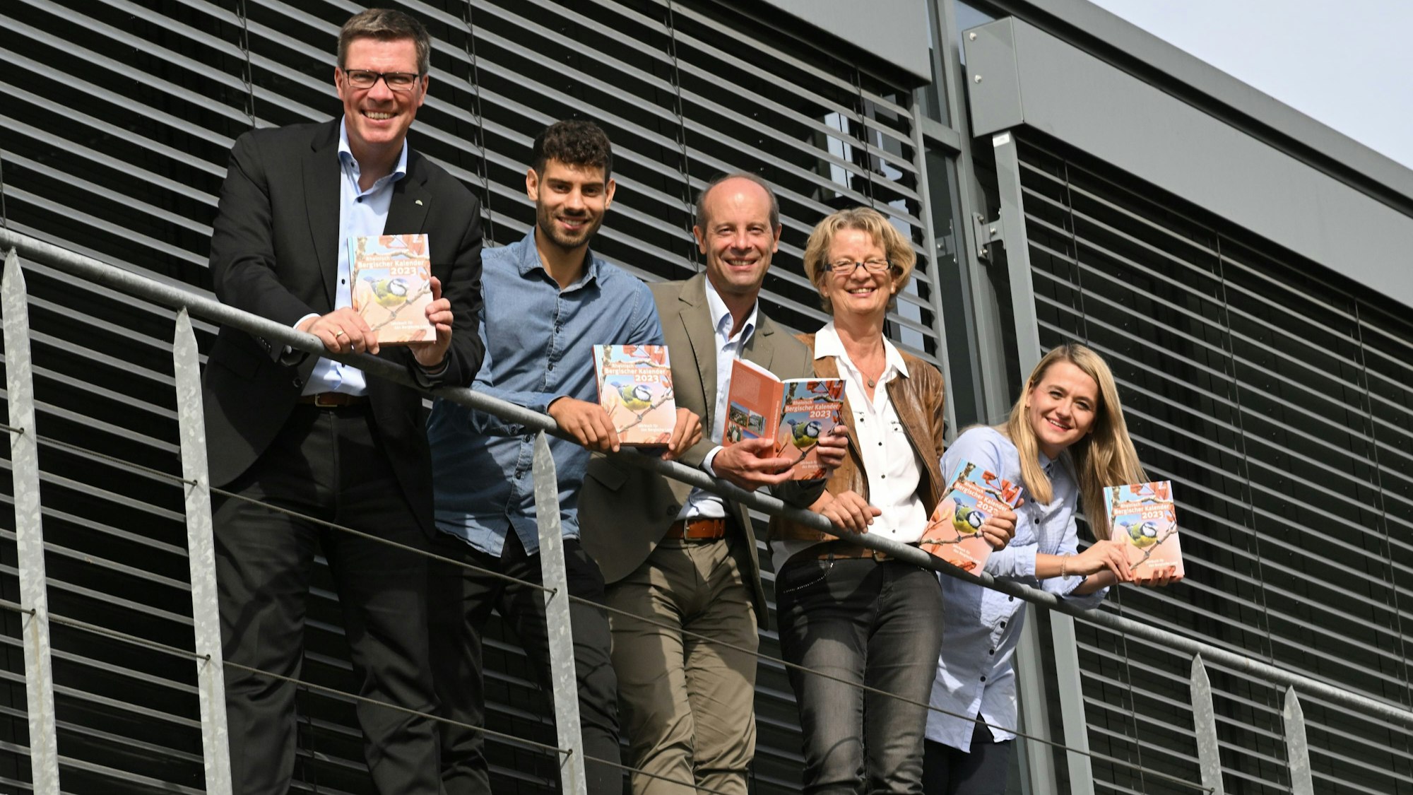 Landrat Stephan Santelmann, Claudio Heider, Hans-Martin Heider, Karin Grunewald und Charlotte Loesch stehen nebeneinander mit einem Kalender-Exemplar auf einer Empore.