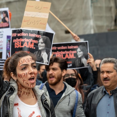 Eine Frau demonstriert in der Kölner Innenstadt. Im Hintergrund halten mehrere Menschen Schilder in die Luft.