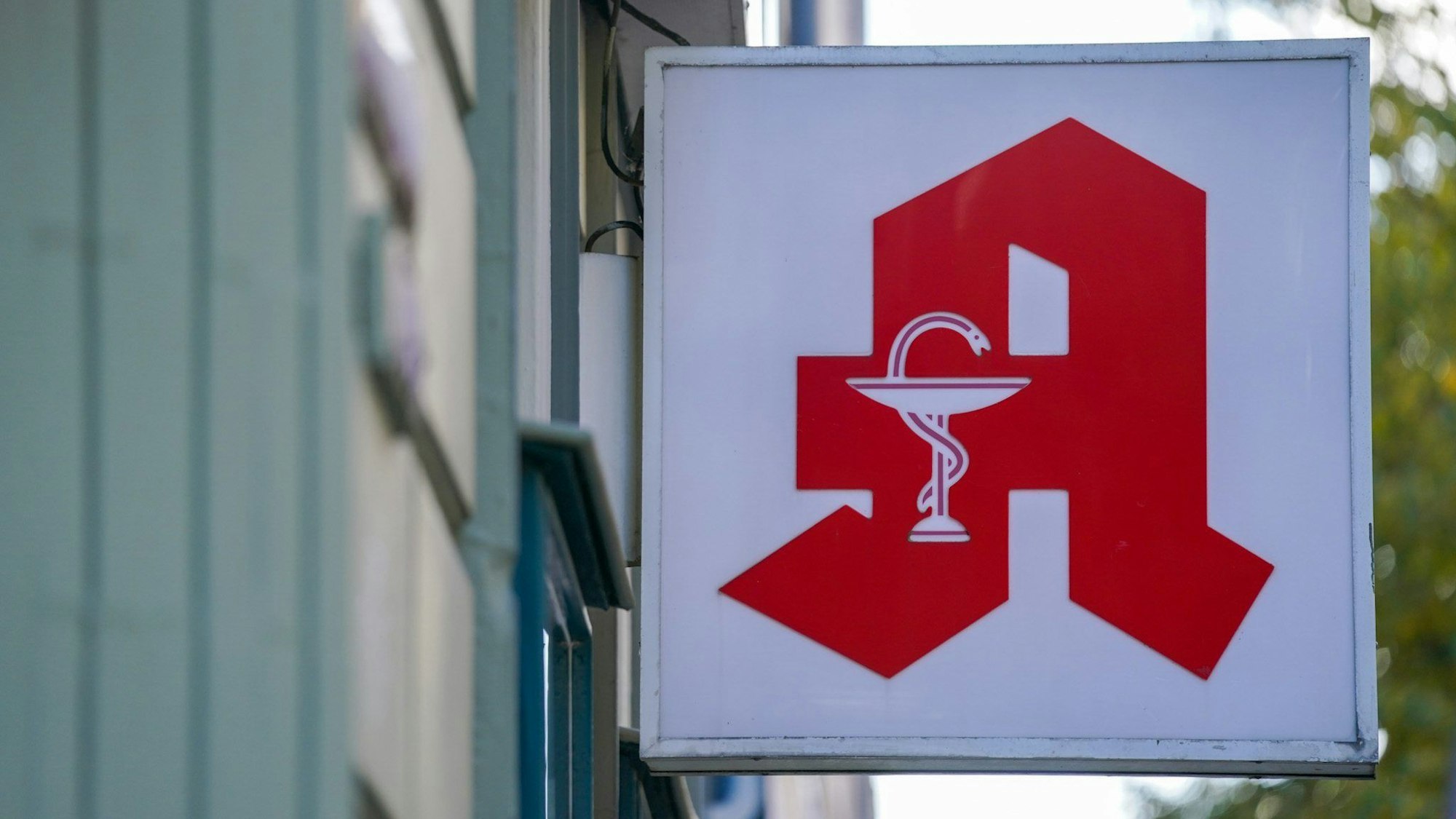 Ein Schild einer Apotheke hängt außen an einem Geschäft.