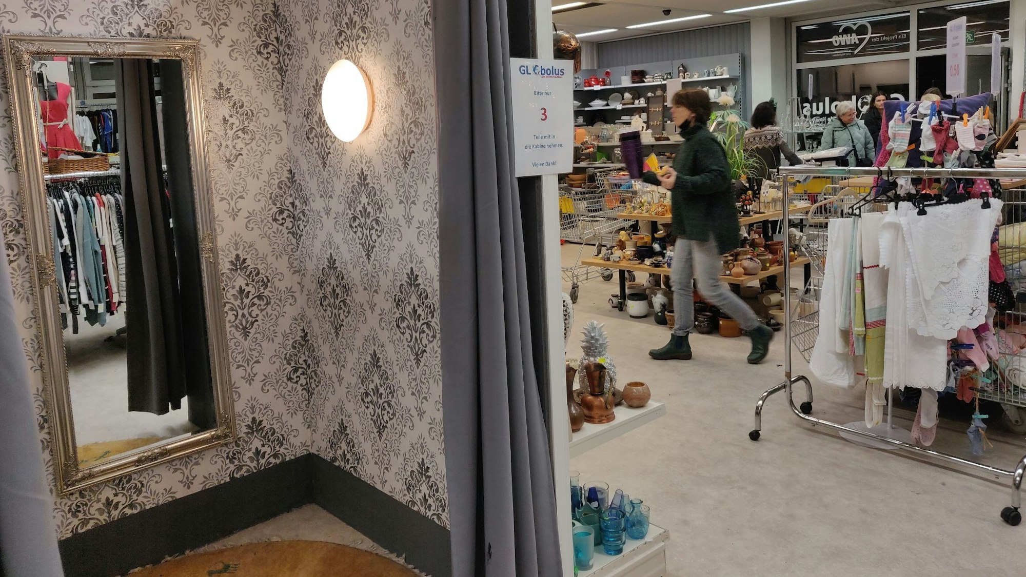 Blick in die tapezierte leere Umkleidekabine mit Spiegel im Sozialkaufhaus in Leichlingen.