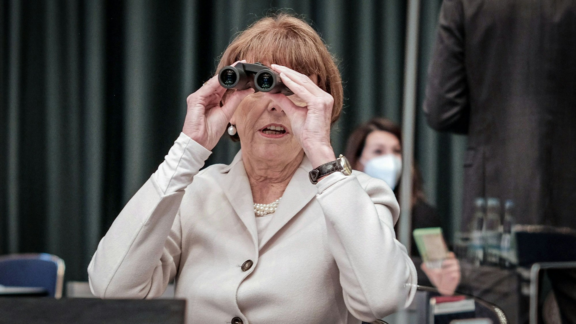 Oberbürgermeisterin Henriette Reker nutzt im Februar 2022 während der Ratssitzung ein Fernglas, um im großen Sitzungssaal des Gürzenich die hinten sitzenden Ratsmitglieder zu erkennen. Wegen der Corona-Pandemie galten besondere Abstandsregeln.
