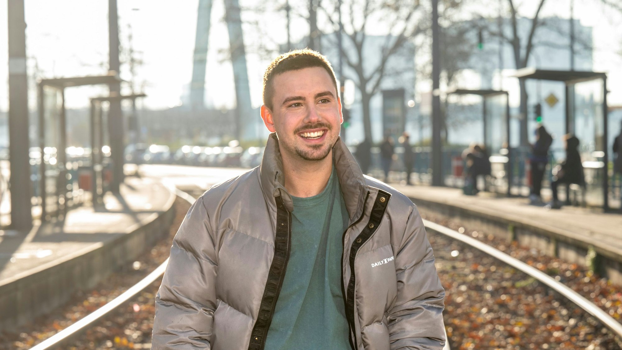 Sänger Sebastian Wurth, Ex-Mitglied der Schlager Boyband „Feuerherz“, will nun solo mit Popmusik auf Deutsch durchstarten. Er steht in Winterjacke an der Haltestelle Deutzer Freiheit.