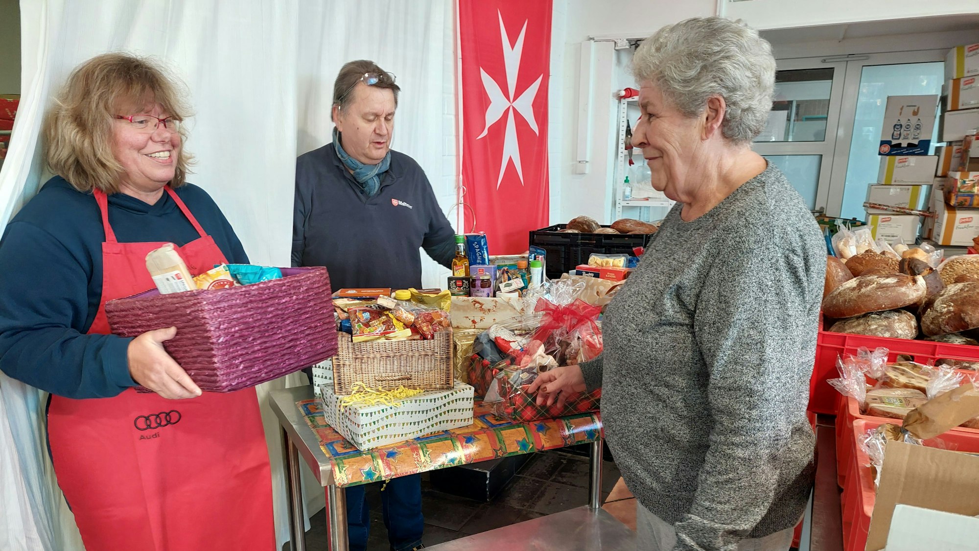 Malteser Tafel: Das Bild zeigt Petra Drehert und  Gerhard Kunst, die die Tafel an der Steinstraße 6 leiten, mit einer Kundin.