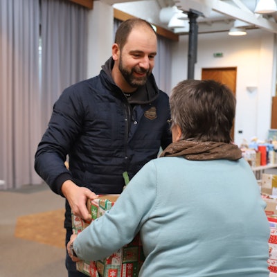 Ein Mann übergibt einen Karton mit Spenden.