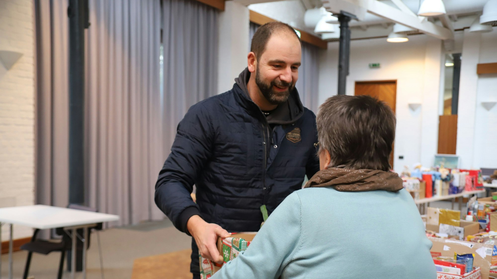Ein Mann übergibt einen Karton mit Spenden.