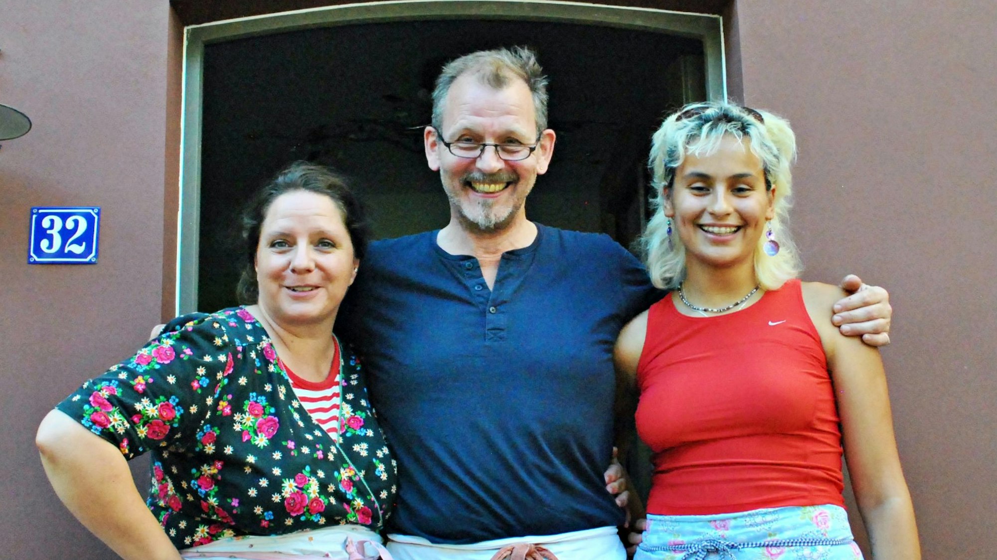 Die drei stehen unter dem Schriftzug Herzhäuschen im Cafeeingang.