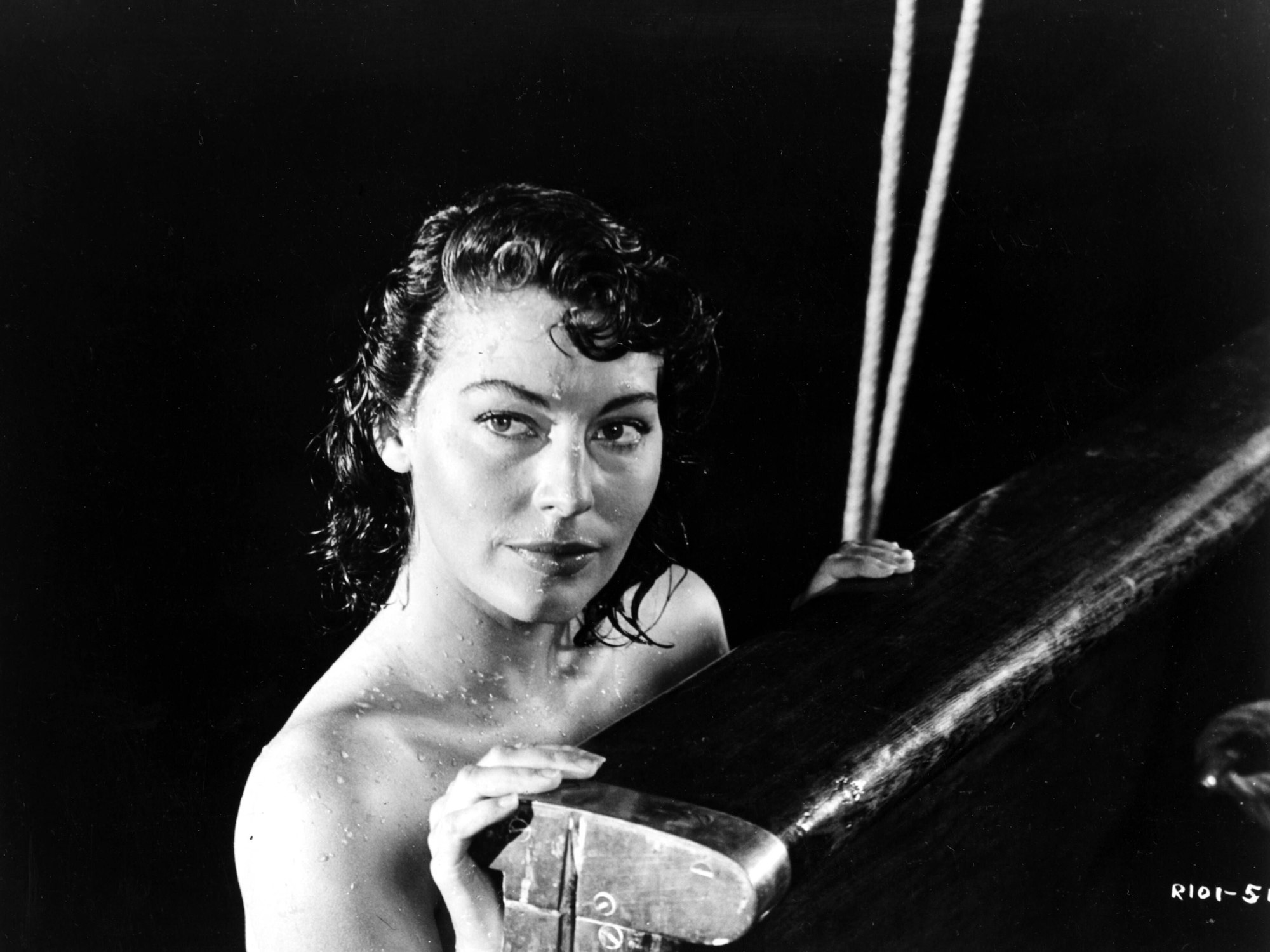 Ava Gardner im Meer, die sich an einem Boot festhält.