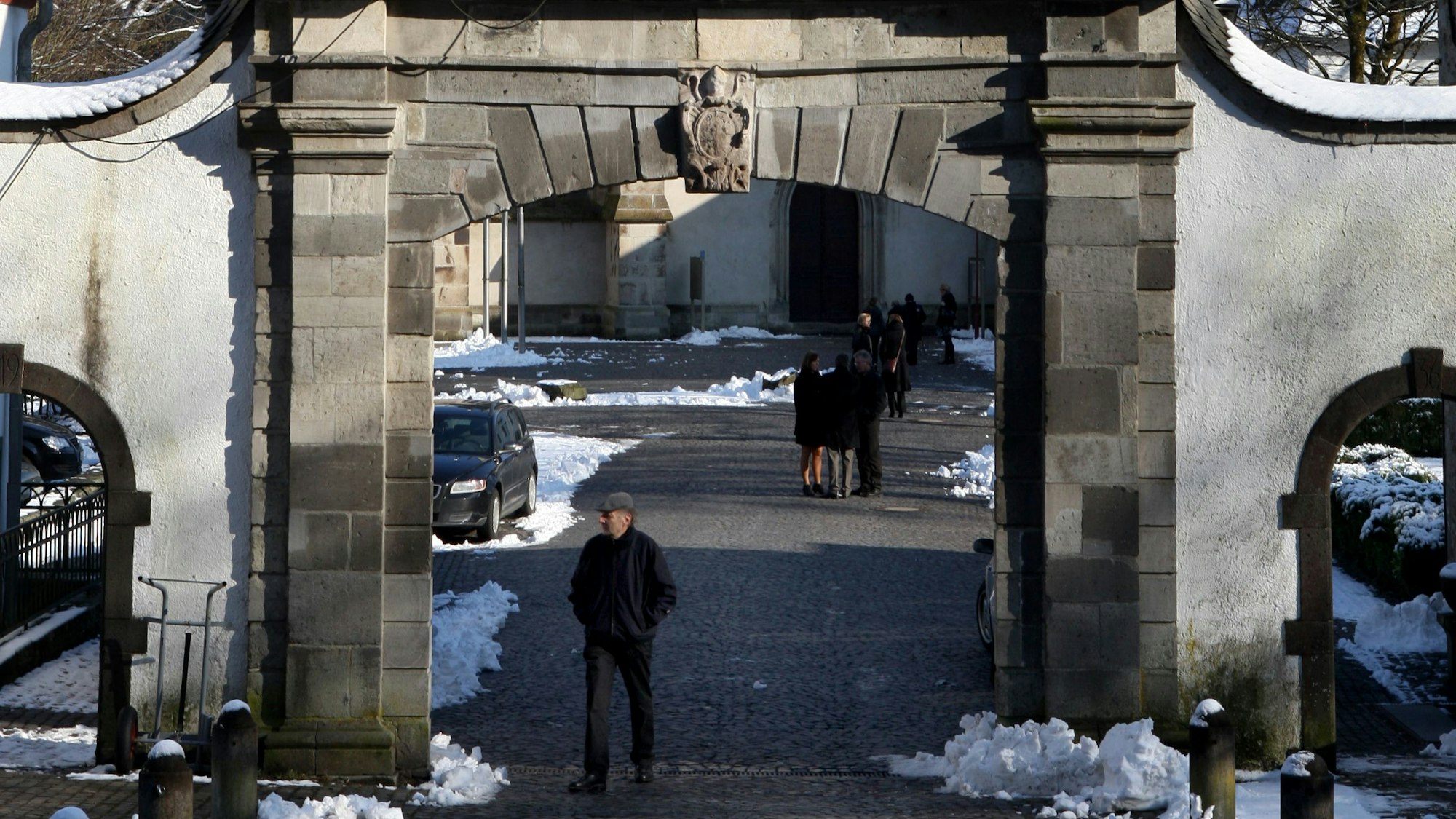 Ein Mann geht durch eine barocke Pforte.
