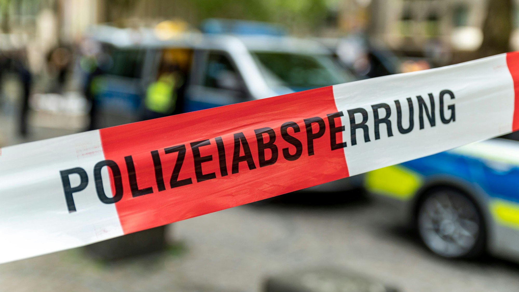 Ein Polizeiwagen steht hinter einer Absperrung.