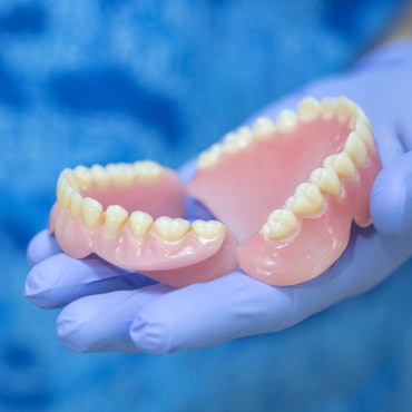 Eine Person hält ein Gebiss in der Hand und präsentiert es.