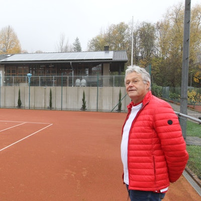 Zwei Männer in blauer und roter Jacke stehen auf einem Tennisfeld.